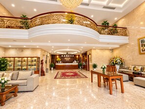 A hotel lobby with a reception desk, seating area, and a decorative staircase. - Moonlight Da Nang Hotel (Da Nang)