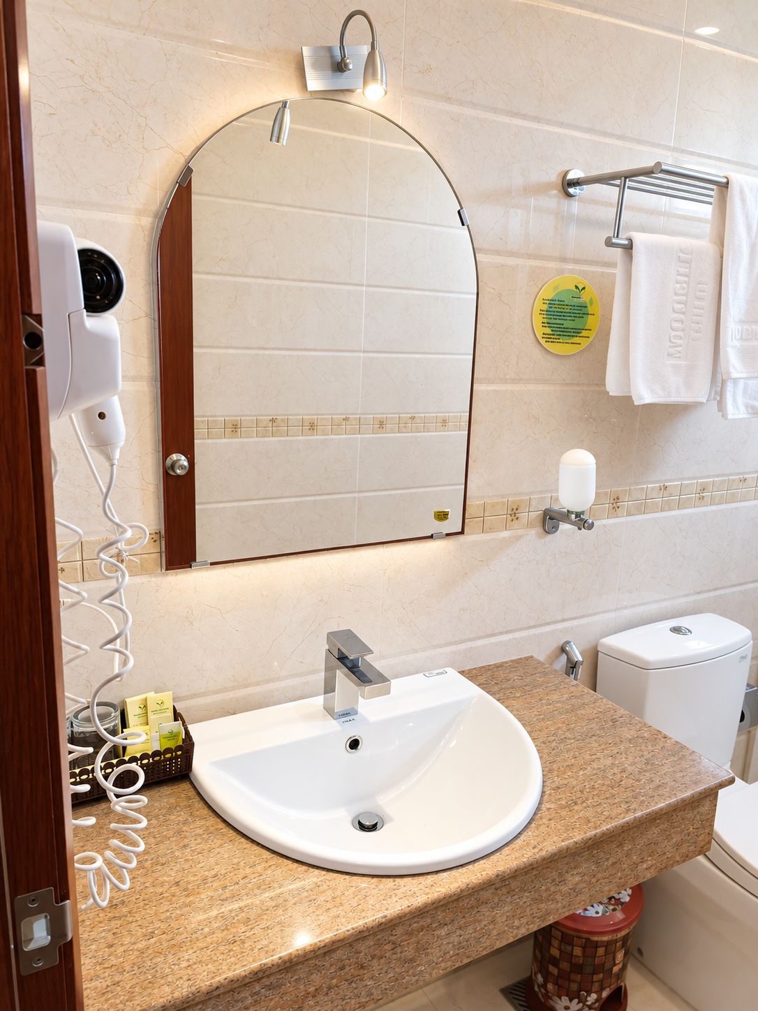 Ein Badezimmer mit Waschbecken, Spiegel, Handtuchhalter und Toilette.