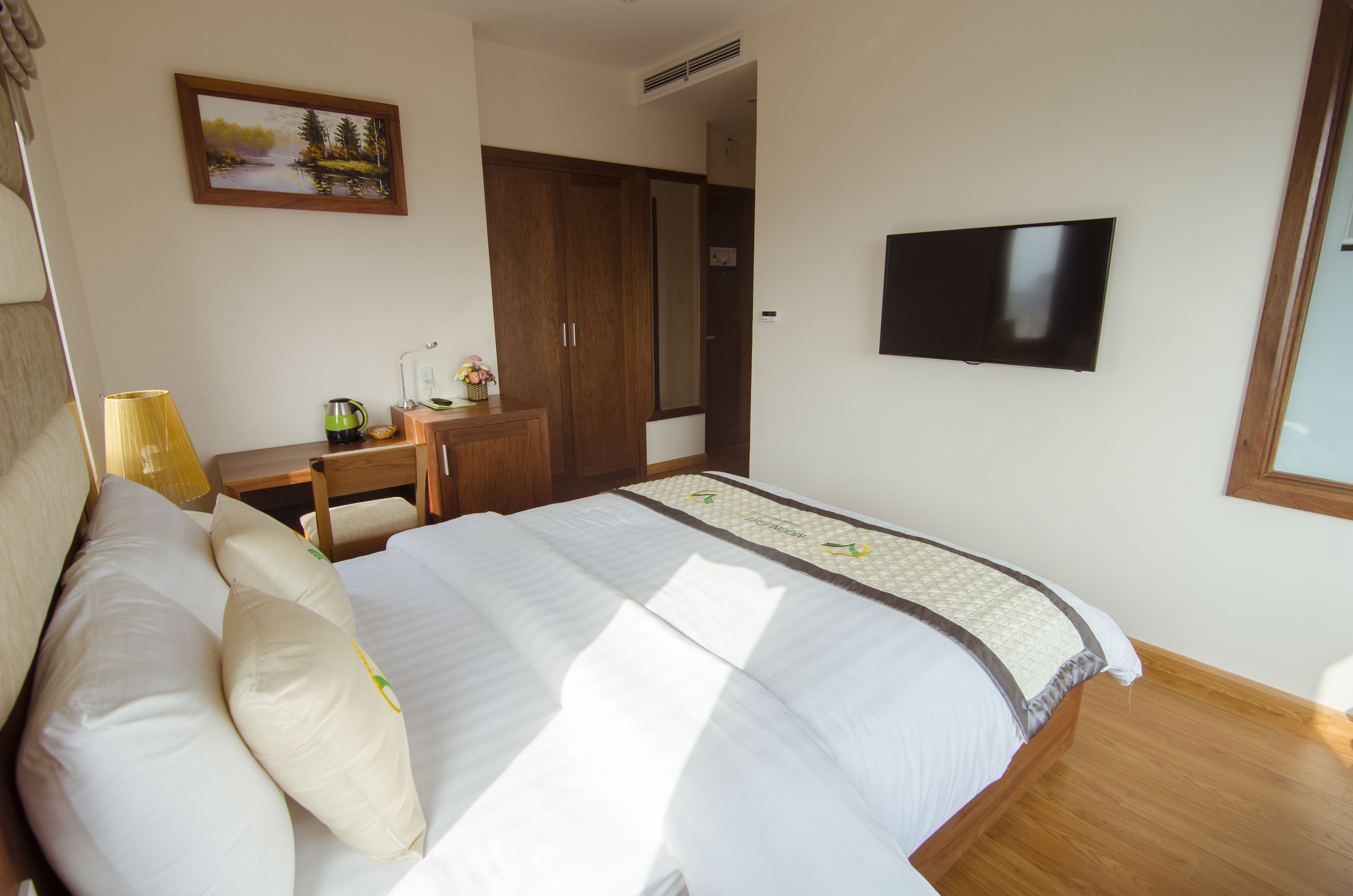 A bedroom with a bed, a desk, a chair, a television, and a wardrobe.