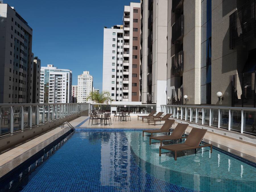 Una piscina al aire libre con sillas de descanso, rodeada de edificios altos.
