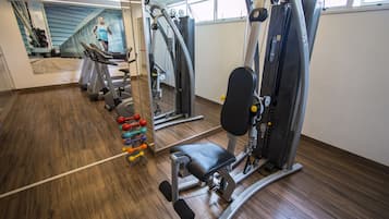A gym with exercise equipment, a treadmill, and a mirror reflecting the room.