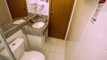 Een badkamer met twee wasbakken, een toilet en een douche.