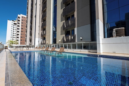 Una piscina al aire libre, sombrillas, sillones reclinables de piscina