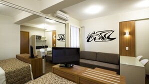A modern hotel room with a flat-screen TV, a sofa, a desk, and a mirror.