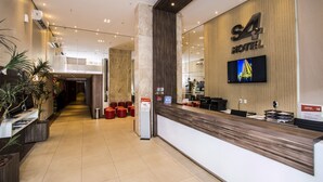 A hotel reception area with a modern design, a reception desk, and a television screen.