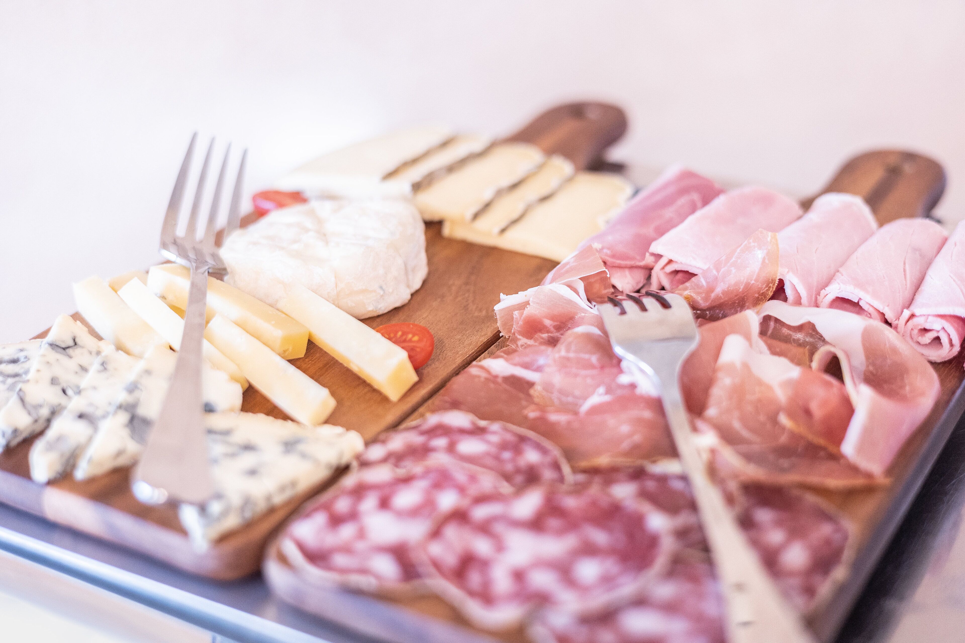 Une sélection de fromages et de charcuteries présentés sur une planche en bois.