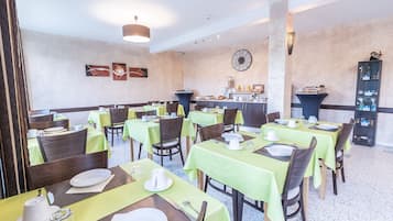 A restaurant with multiple tables set for dining, featuring green tablecloths and brown chairs.
