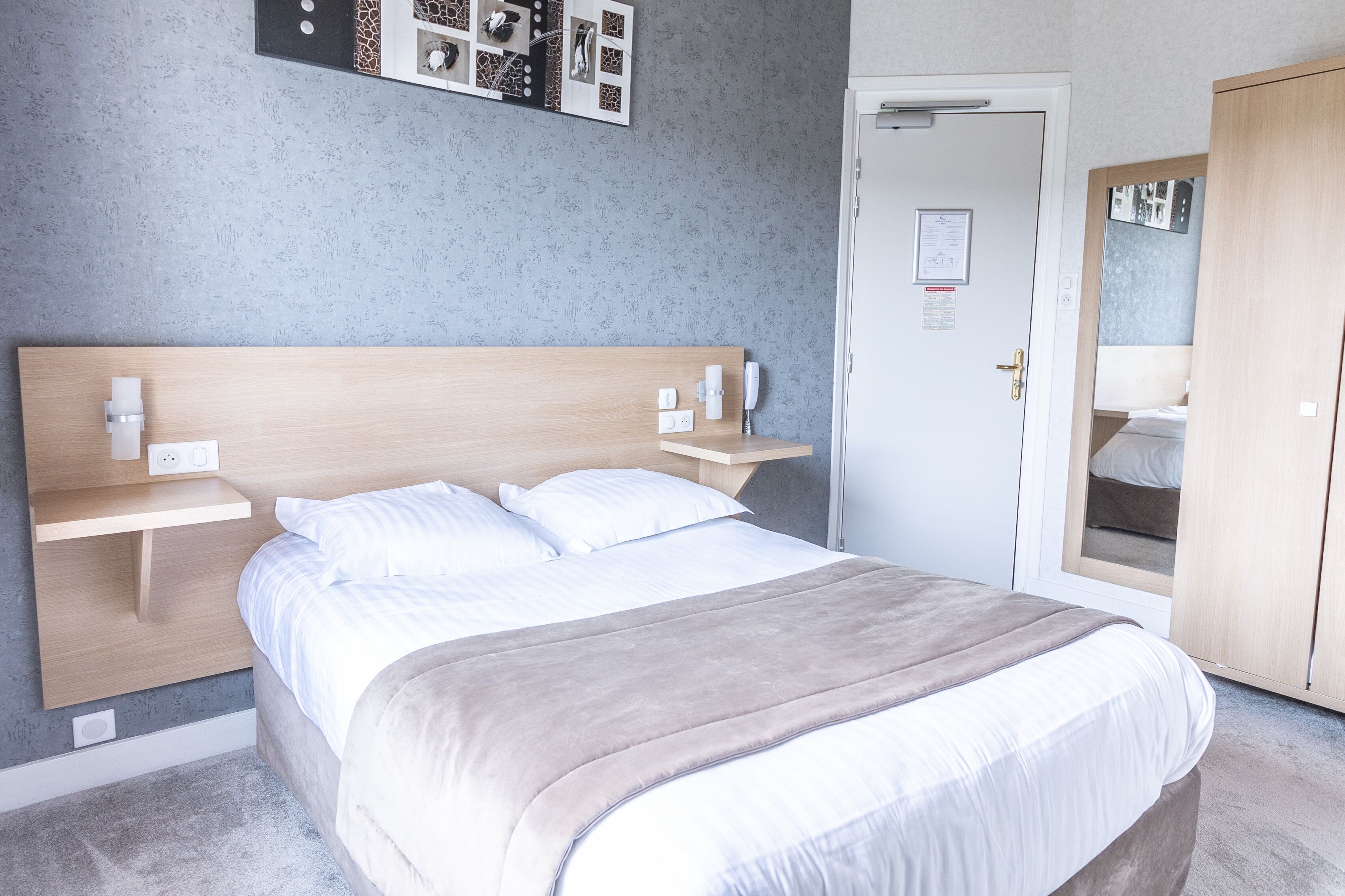 A neatly arranged bedroom with a bed, bedside tables, a wardrobe, and a door.