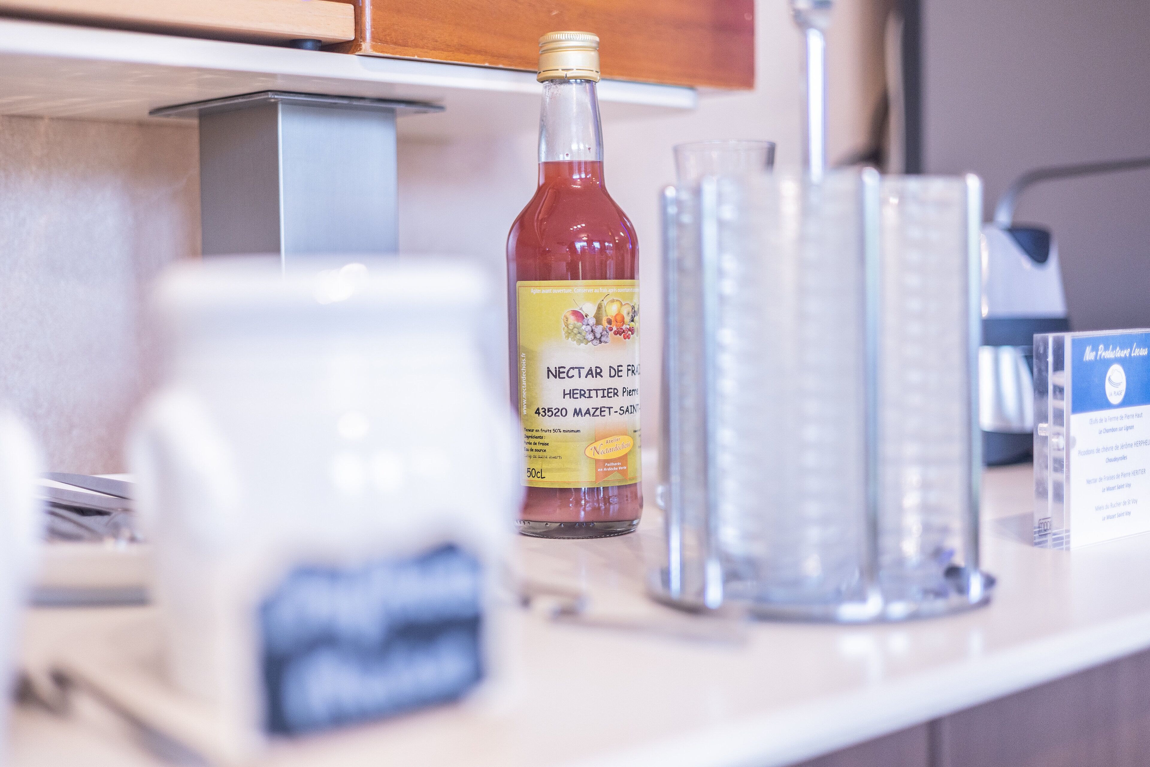 A kitchen counter with a bottle of Nectar de Heritier, a glass container, and a measuring cup.