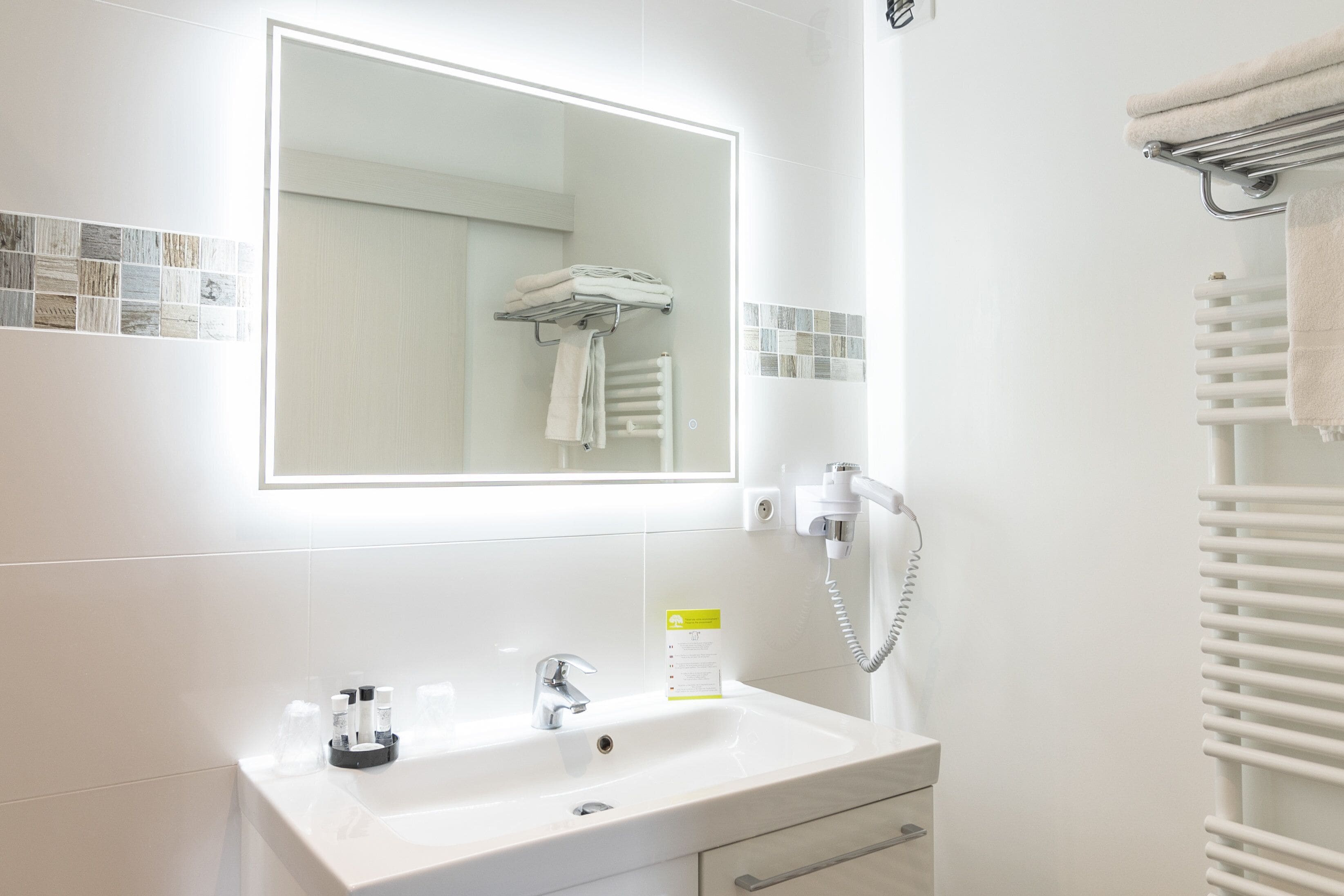 A modern bathroom with a white sink, a mirror, and a towel rack.