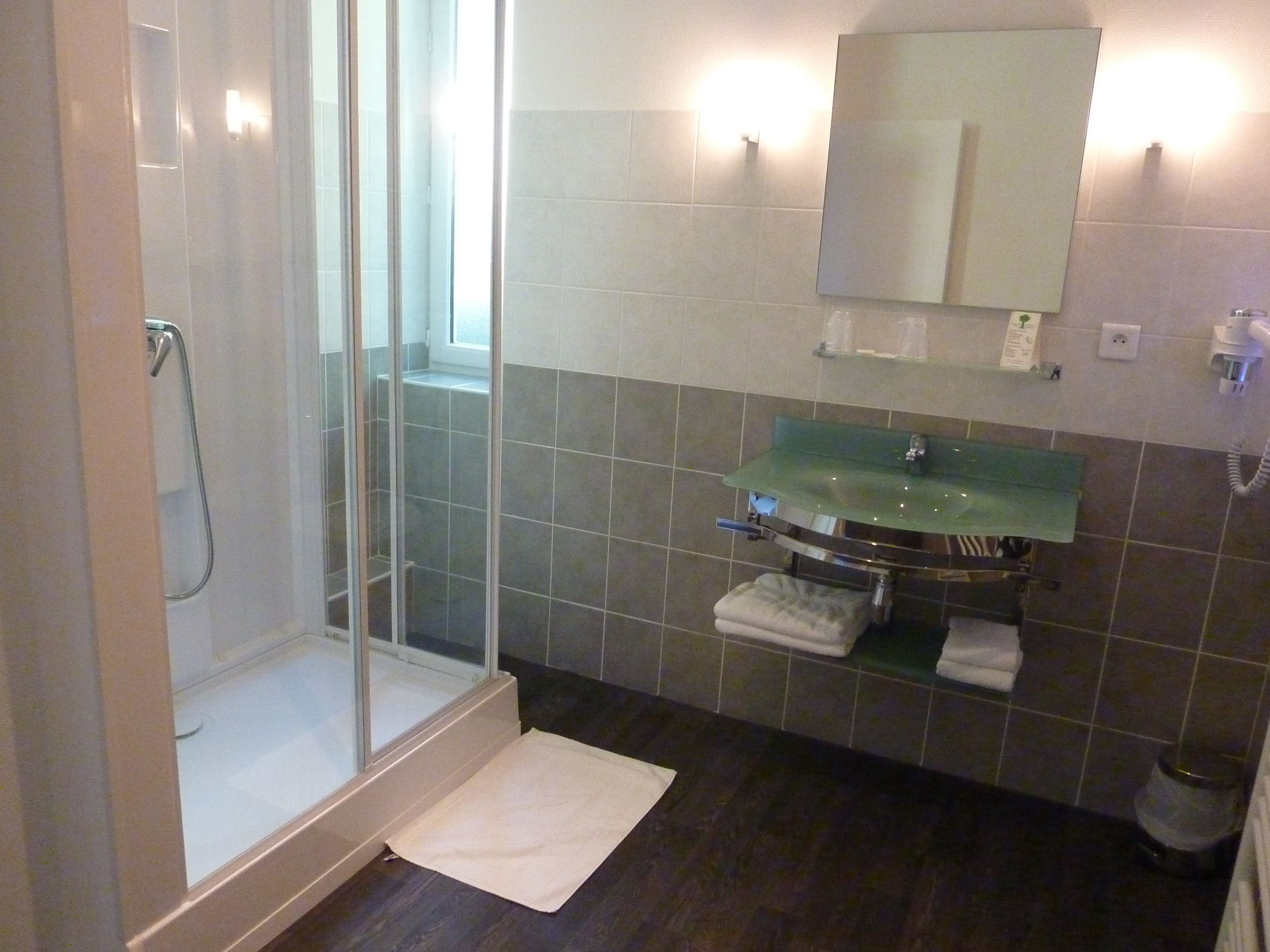 Un baño con cabina de ducha de vidrio, un lavabo verde y un espejo encima.