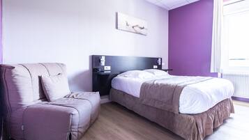 Een slaapkamer met een bed, een bank, een nachtkastje en een aan de muur hangend kunstwerk.