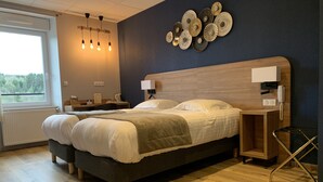 Un dormitorio moderno con una cama grande, mesitas de noche, un escritorio y vistas al exterior.