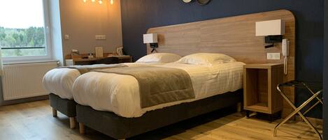 A modern bedroom with a large bed, bedside tables, a desk, and a view of the outdoors.