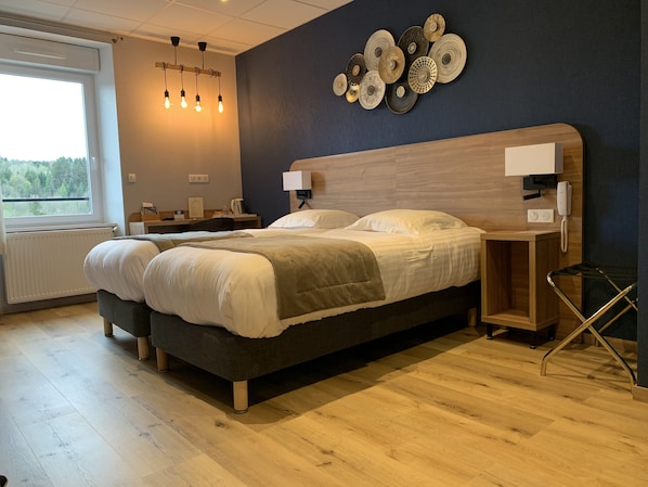 A modern bedroom with a large bed, bedside tables, a desk, and a view of the outdoors. - Hôtel de la Plage (Le Chambon-sur-Lignon)
