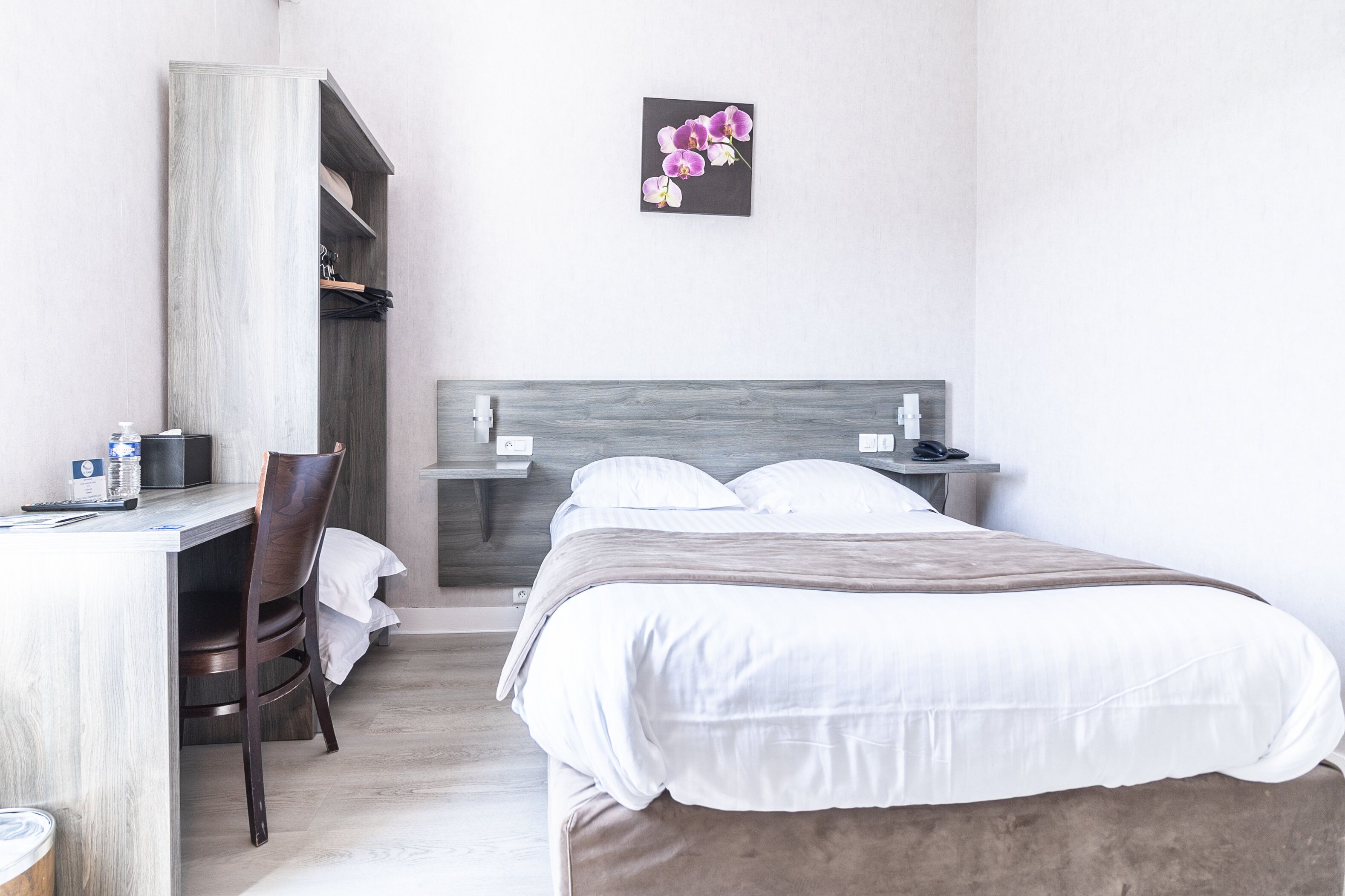 Una habitación de hotel con cama, escritorio, silla y armario.