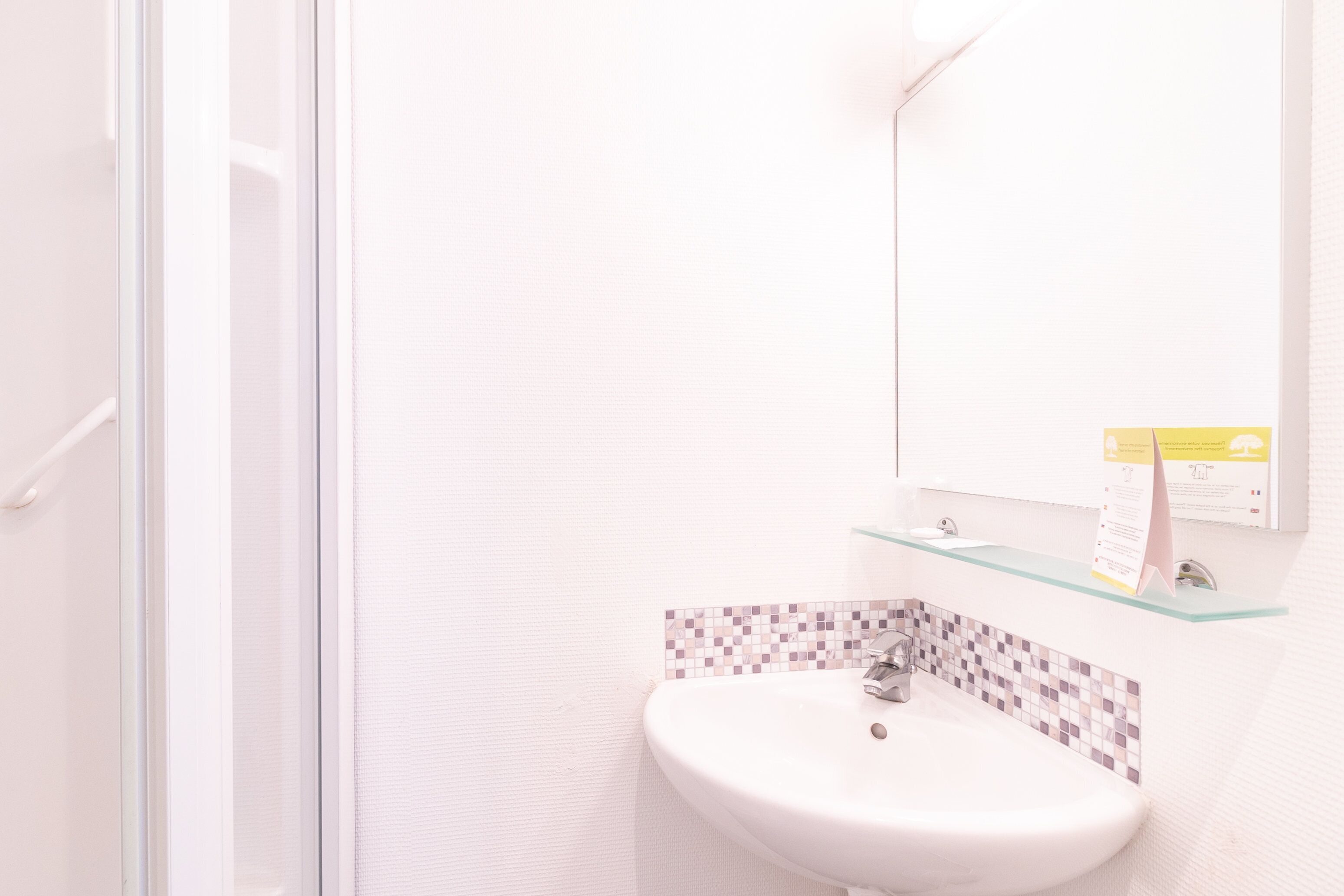 A bathroom with a white sink, a glass shelf, and a tiled backsplash.
