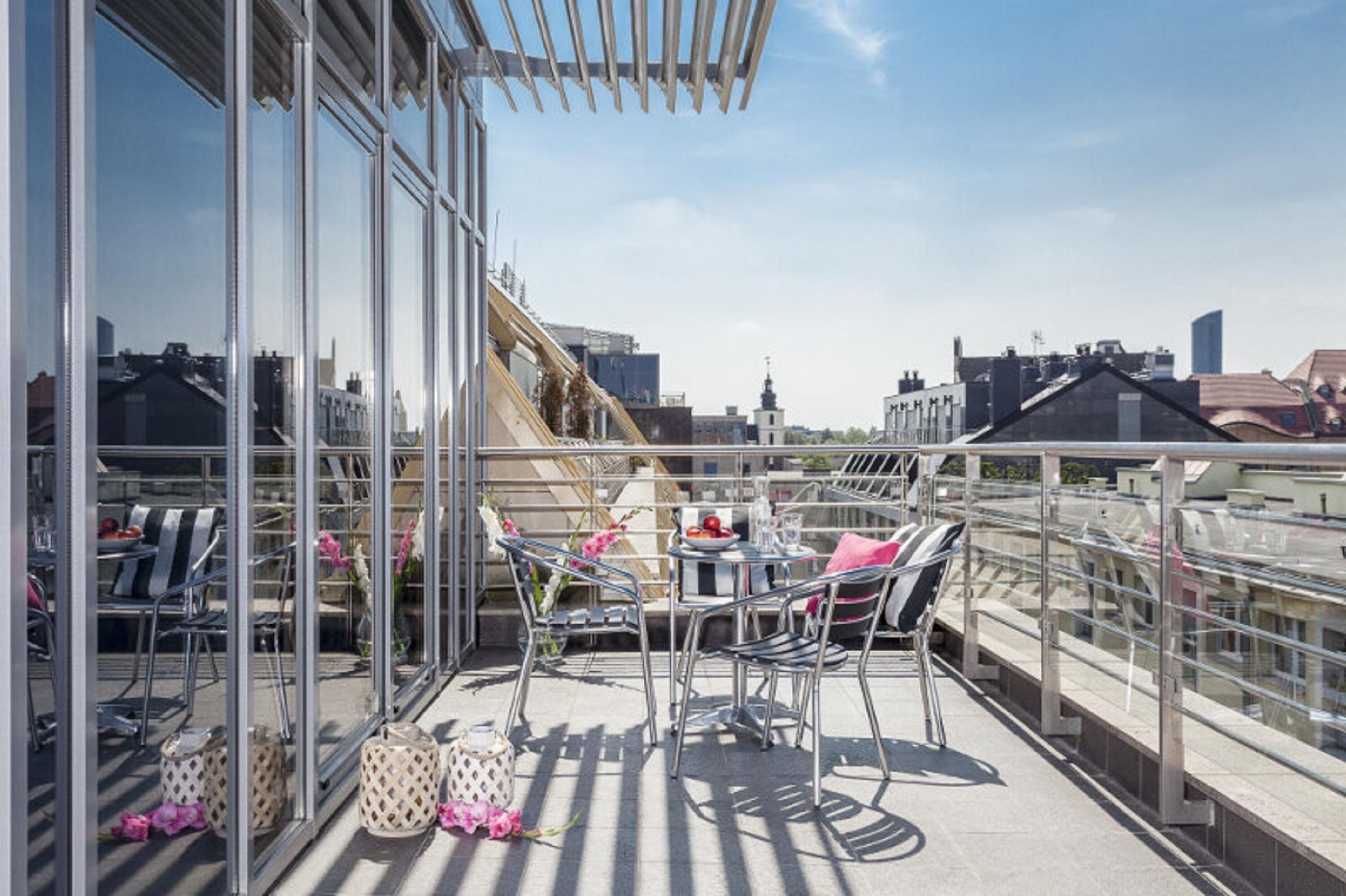 Une terrasse sur le toit avec des garde-corps en verre, des sièges d’extérieur et une vue sur la ville.