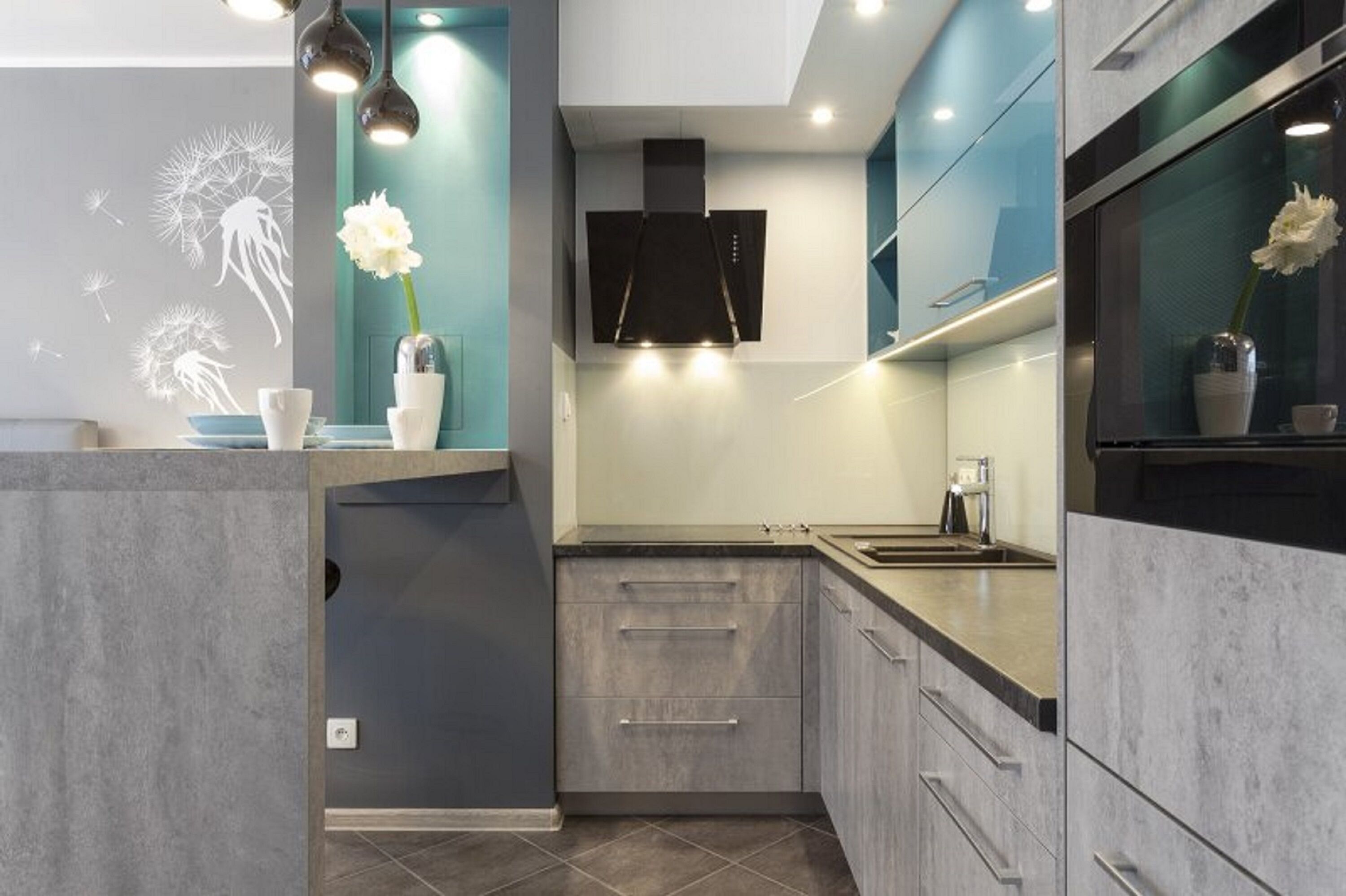 Una cucina moderna con mobili grigi, una cappa aspirante nera e luci a sospensione.