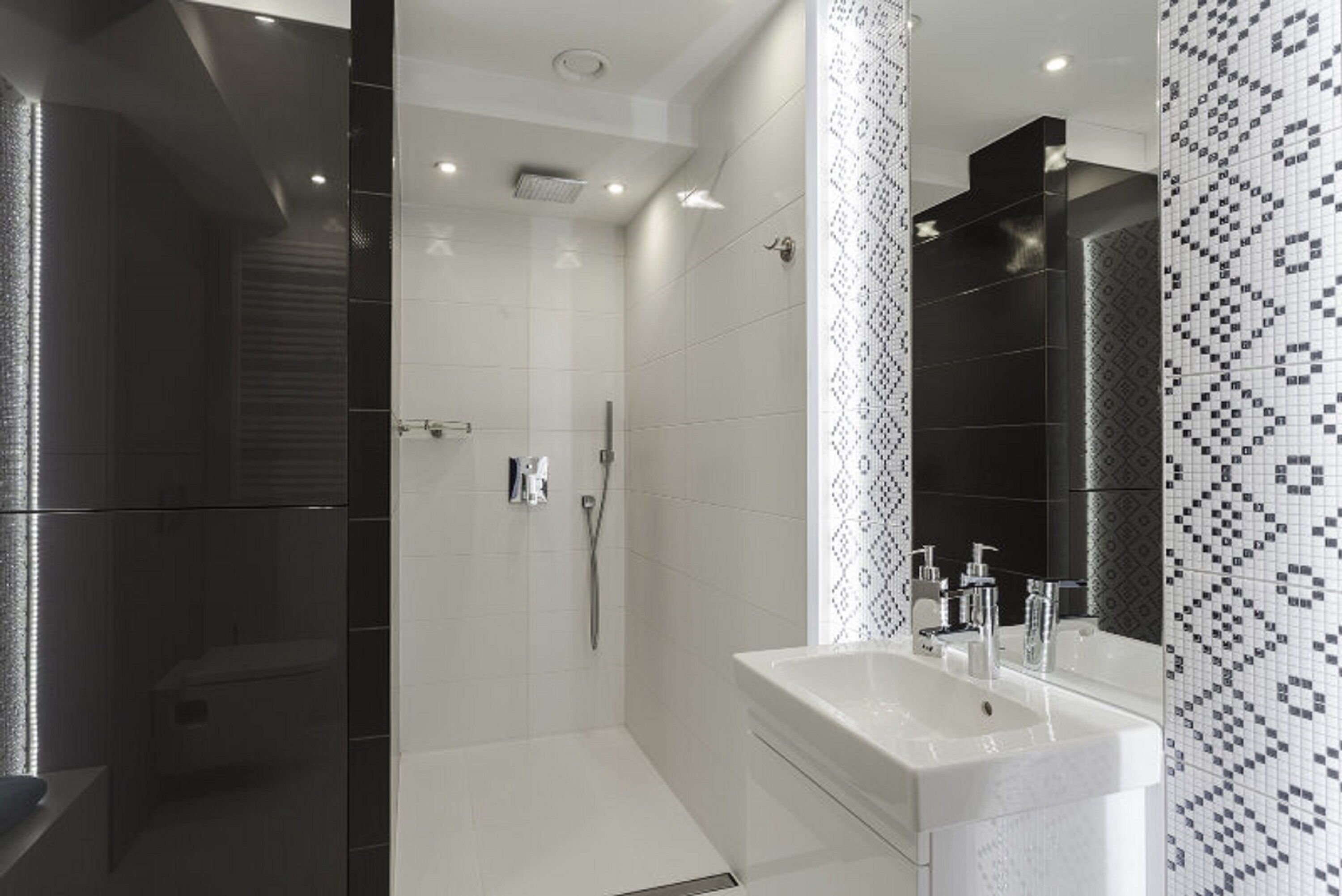 A modern bathroom with a walk-in shower, a large mirror, and a white sink.