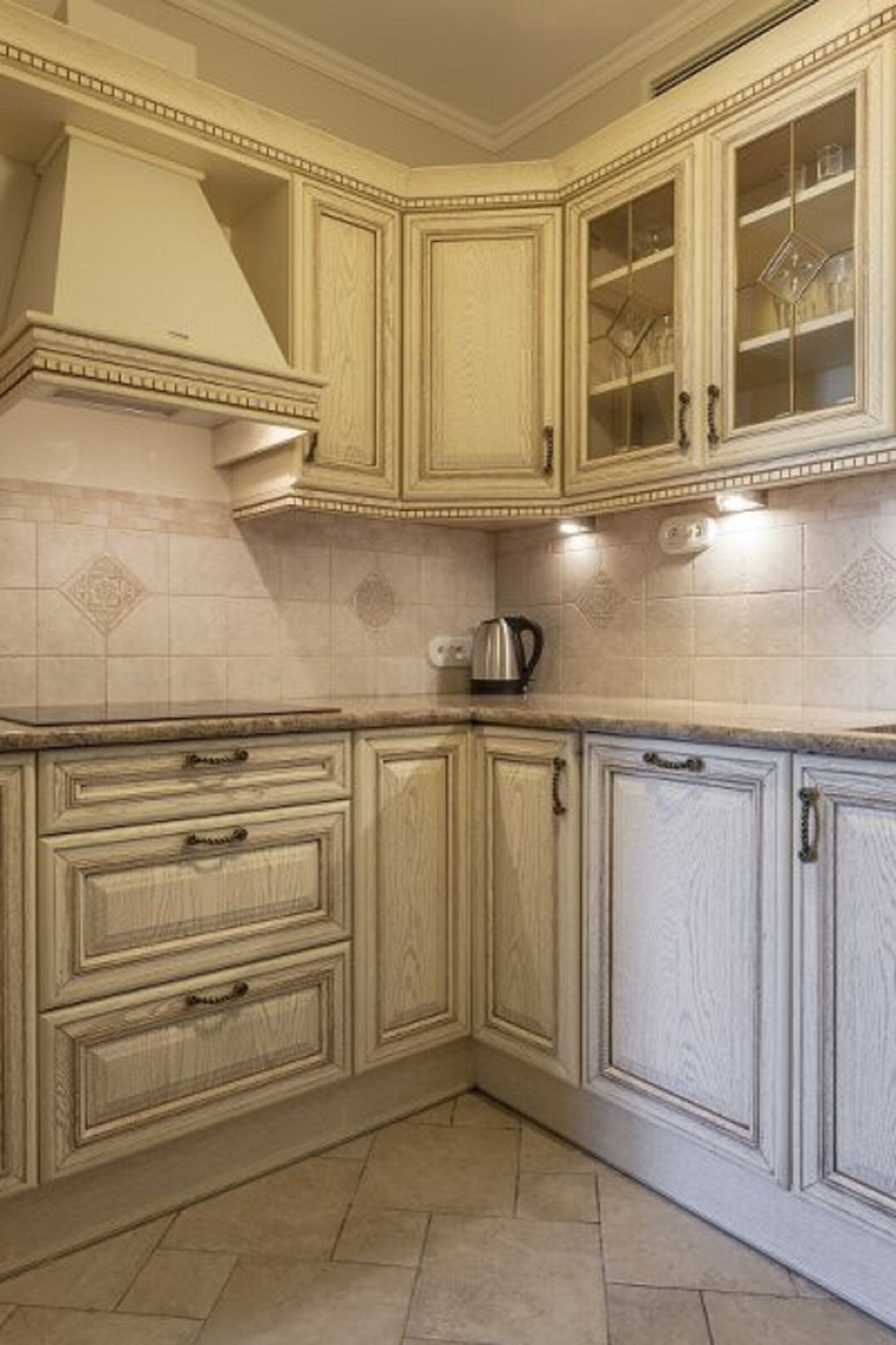 A kitchen with light-colored cabinetry, a stove, and a kettle on the countertop.