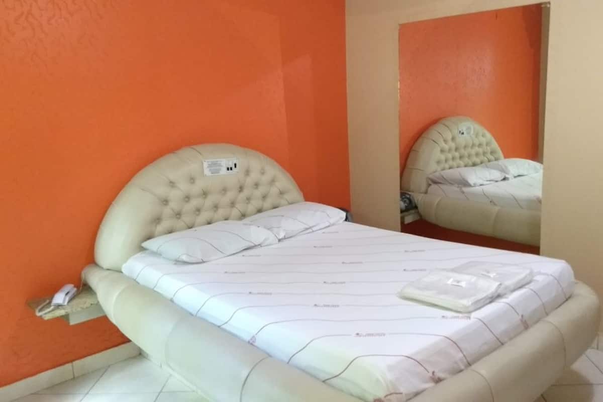 A bed with a headboard, a bedside table, and a mirror.