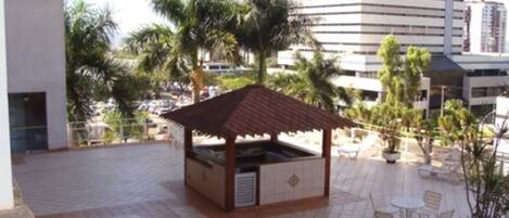 An outdoor patio with a wooden gazebo, tiled flooring, and outdoor seating.
