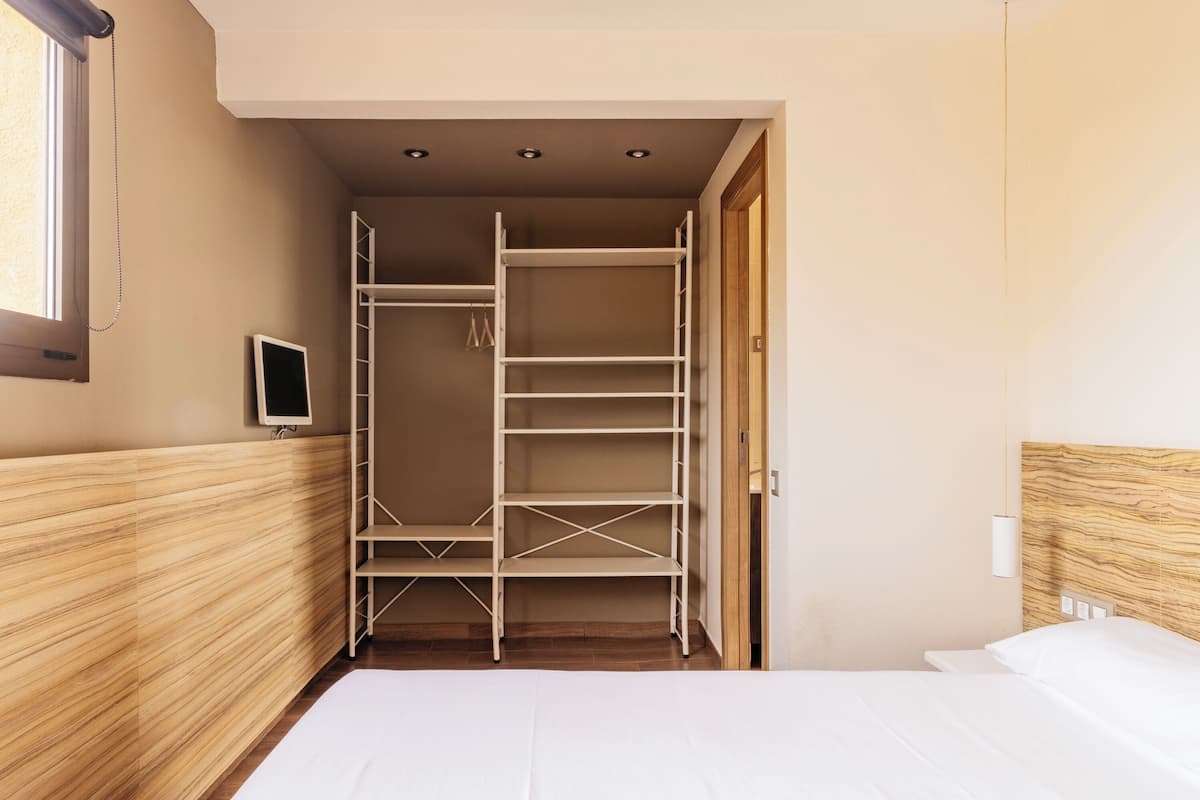 Une chambre à coucher avec un lit, une armoire, un téléviseur et une tête de lit en bois.