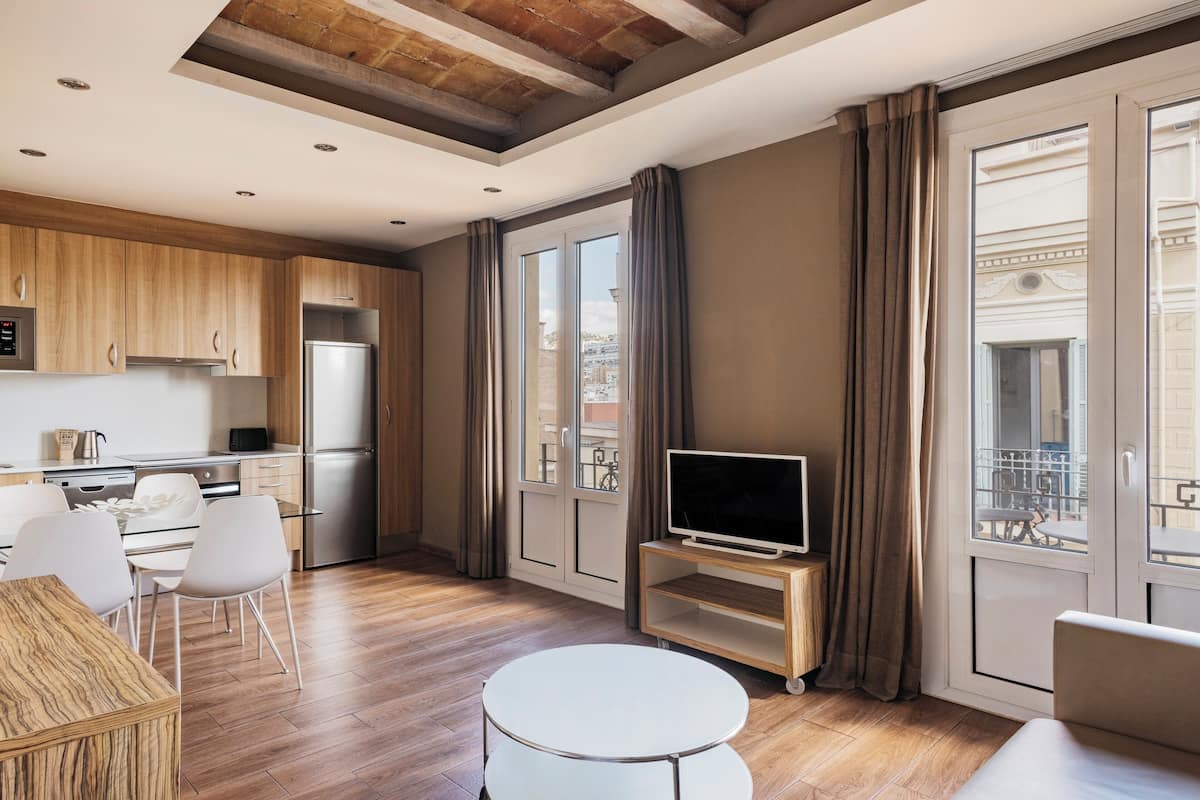 Une cuisine moderne avec des meubles en bois, un réfrigérateur et un coin repas comprenant une table et des chaises blanches.