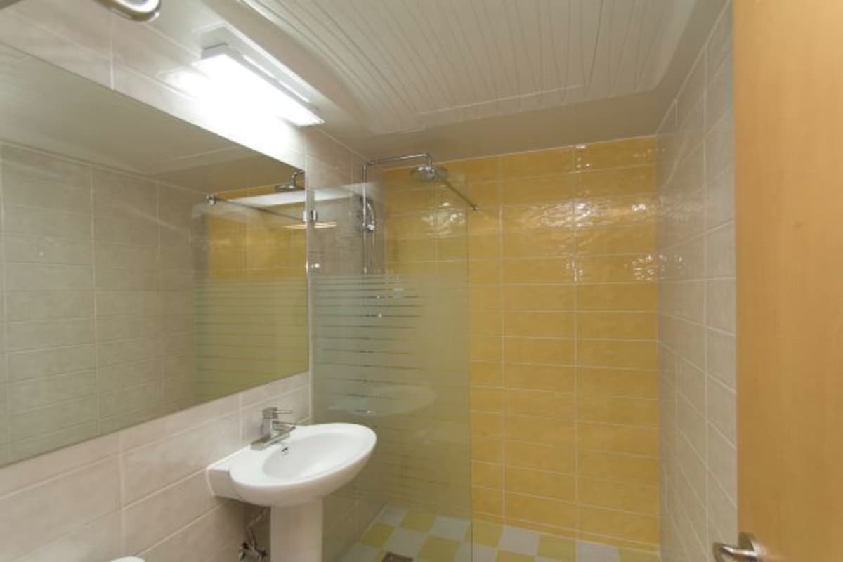 Un baño con lavamanos, espejo y cabina de ducha.