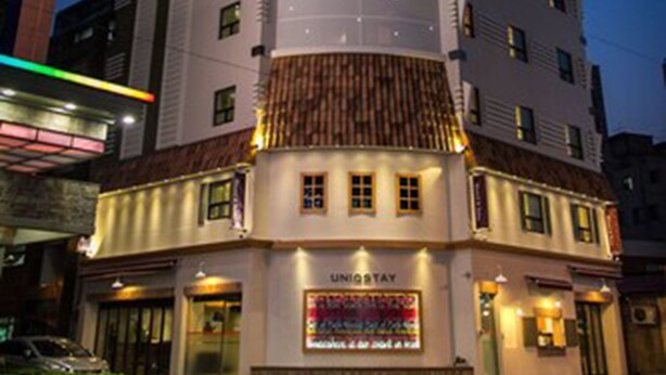 A multi-story hotel with a modern design, featuring a prominent glass facade and a rooftop structure. - Uniqstay (Busan)