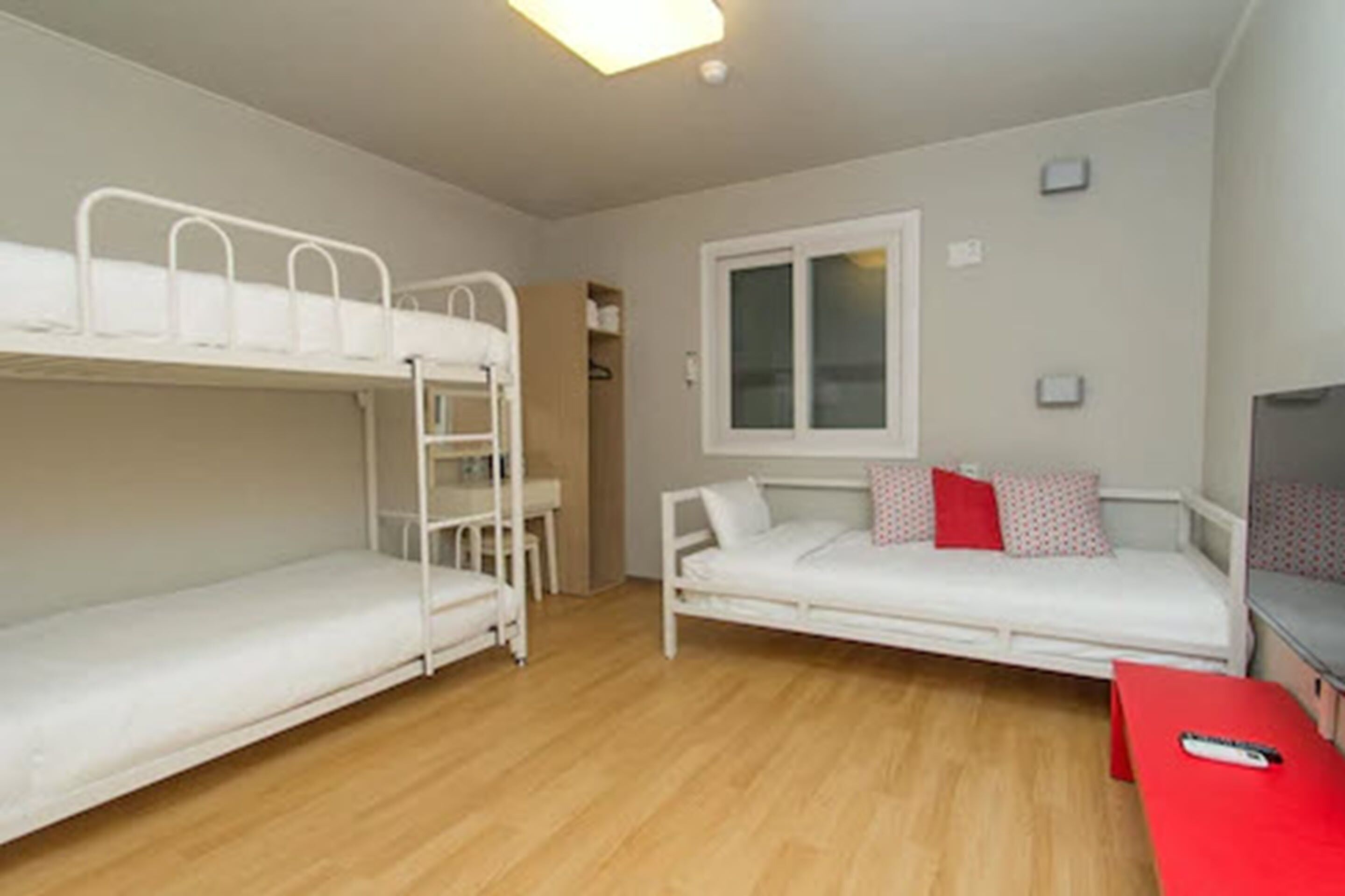 Una habitación con literas, un sofá, una mesita y una ventana.