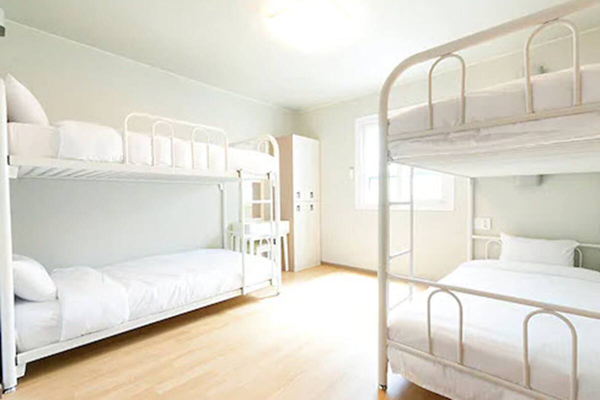 A bunk bed room with white bedding and metal railings.