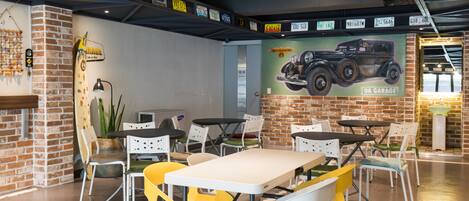 Un espace repas avec des murs en briques, une fresque murale et des tables avec des chaises.