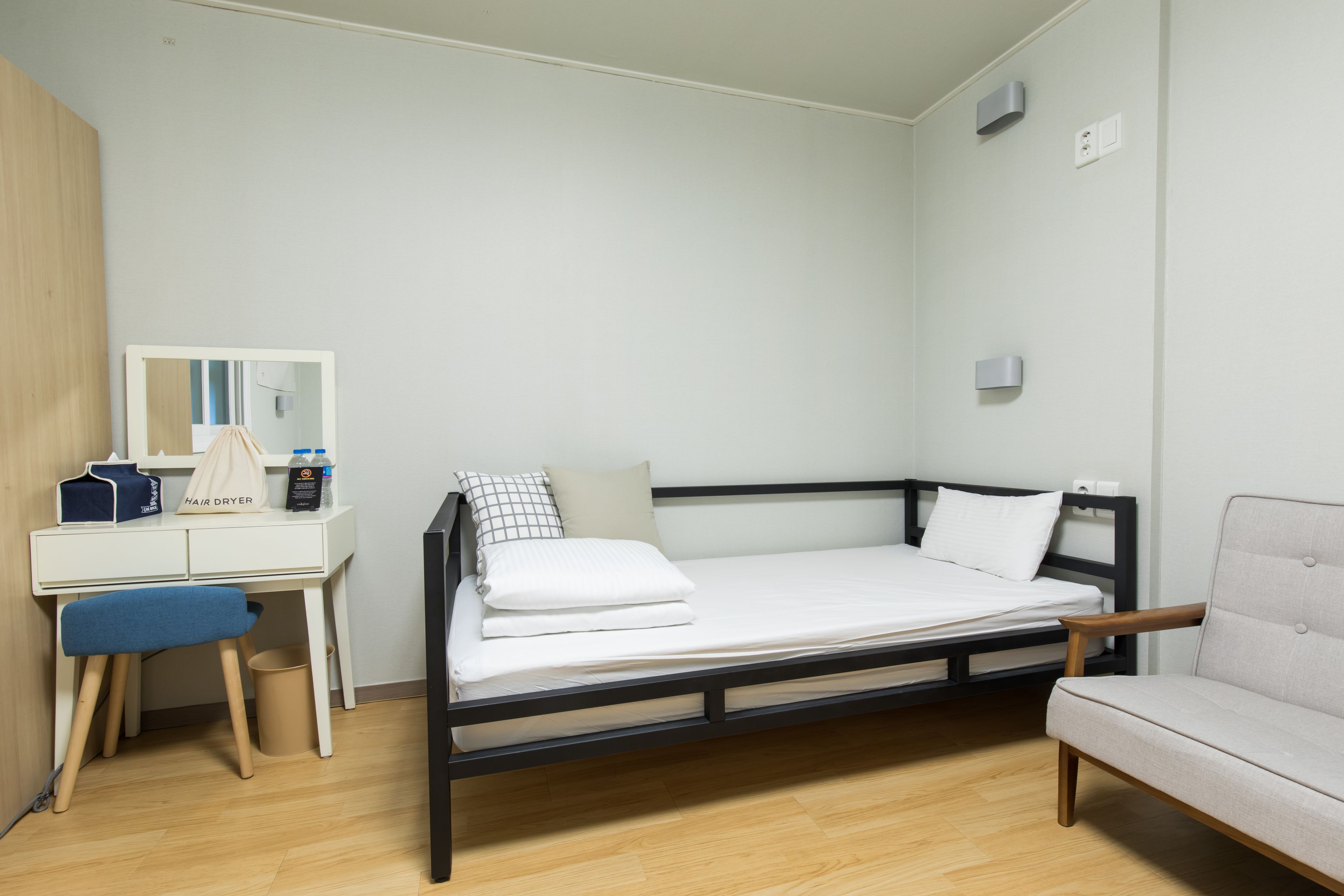 A bedroom with a bed, a desk, a chair, and a mirror.