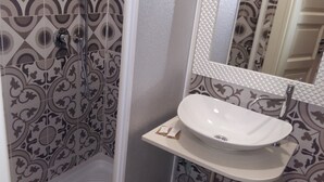 Um banheiro com azulejos estampados, uma pia branca e um espelho com moldura texturizada.