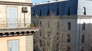 Um edifício com telhado plano, várias janelas e uma varanda com grades.