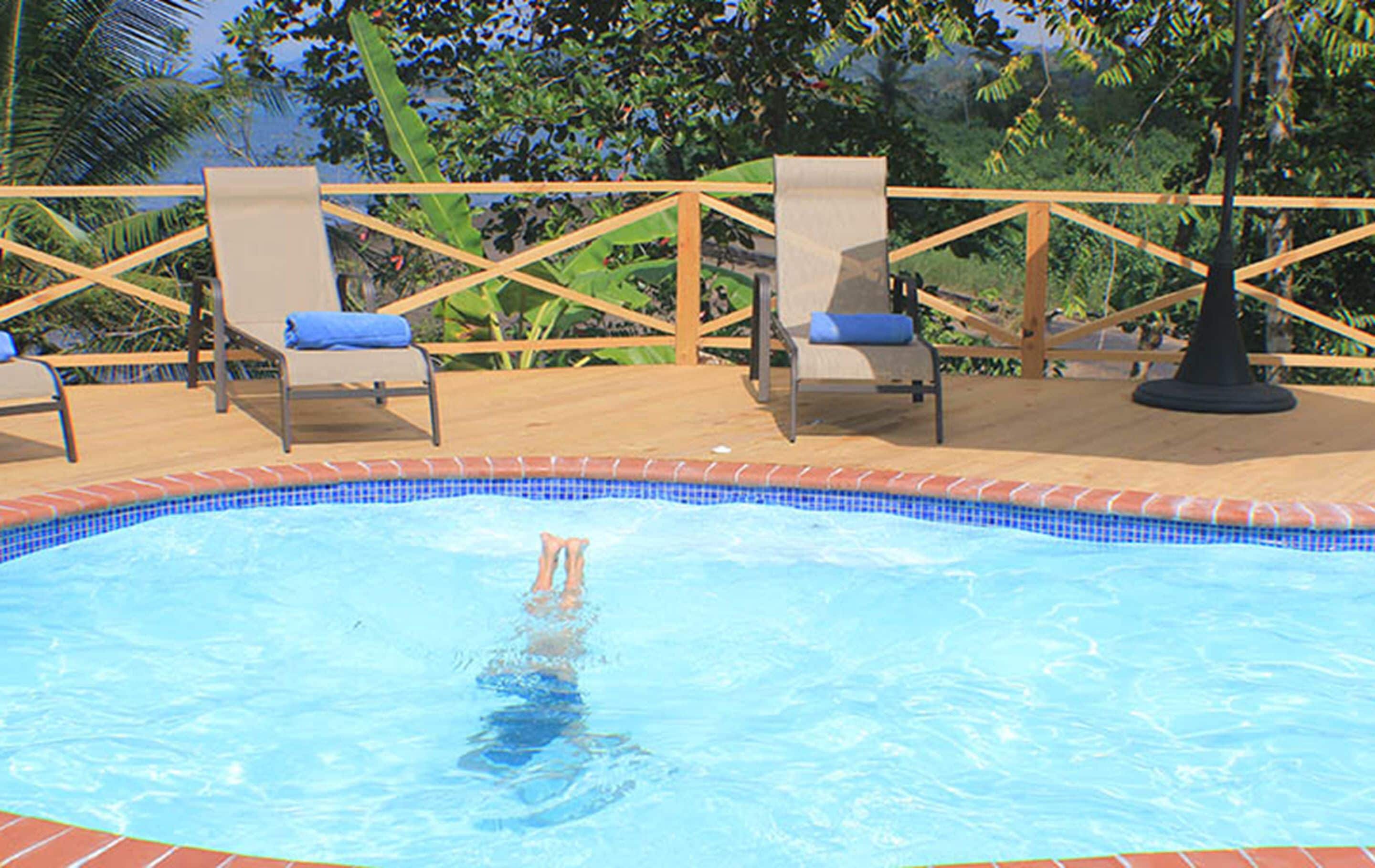 A swimming pool with lounge chairs and a wooden deck.