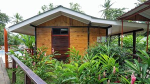 A wooden cabin with a covered porch, surrounded by lush tropical vegetation. - Pirate Cove (Drake Bay)