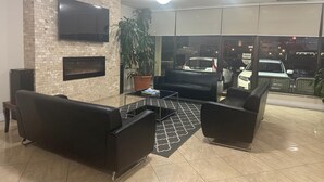 A modern lobby with a brick wall, a flat-screen TV, a fireplace, and a large potted plant. - Nu Hotel Toronto (Mississauga)