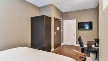 A hotel room with a bed, a desk with a chair, a television, and a wardrobe.