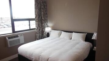 Une chambre d’hôtel avec un grand lit, une fenêtre avec des rideaux, un appareil de climatisation et une lampe de chevet.
