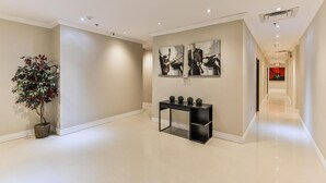 A hallway with a potted plant, a console table with decorative items, and two framed artworks on the wall. - Nu Hotel Toronto (Mississauga)
