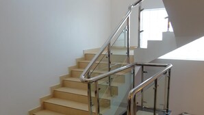 Eine moderne Treppe mit Glastrennstäben und beigefarbenen Stufen, die zu einer oberen Etage führt.