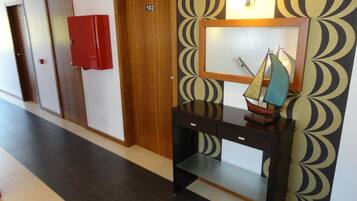 Un pasillo con una puerta de madera con el número 102, un armario rojo y un escritorio con un modelo de velero.
