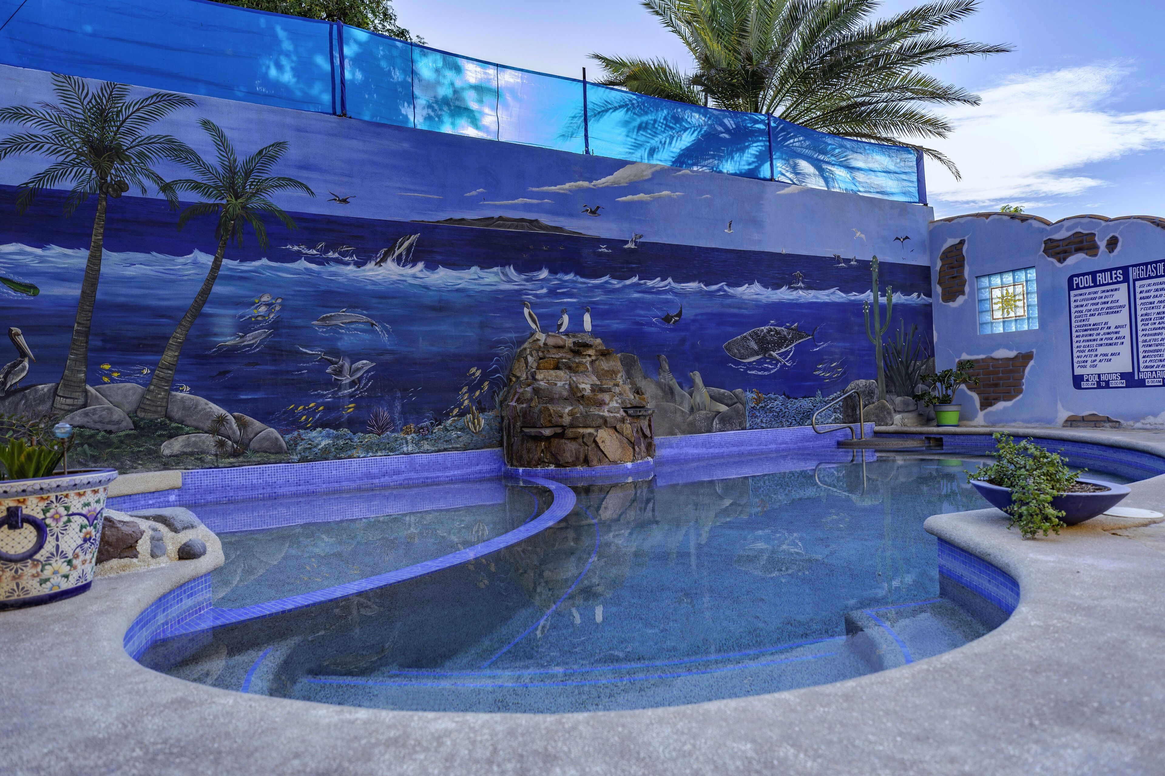 A swimming pool with a mural of ocean wildlife and palm trees.