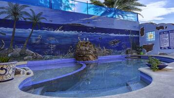 Una piscina amb un mural de fauna marina i palmeres.