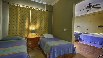 A room with two beds, a ceiling fan, and a window with curtains.