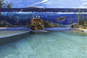 A pool with a mural of ocean and marine life, clear water, and a rock formation. - Posada Luna Sol (La Paz)