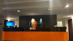 A hotel reception desk with a large 'Ztel' sign, a computer monitor, and a no-smoking sign. - Zotel Hotel (Kuching)
